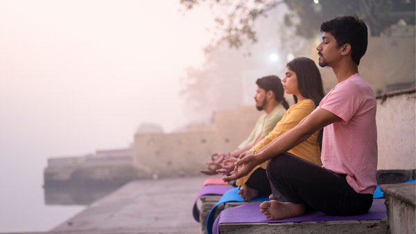 A group of people doing HATHA YOGA on a river bank